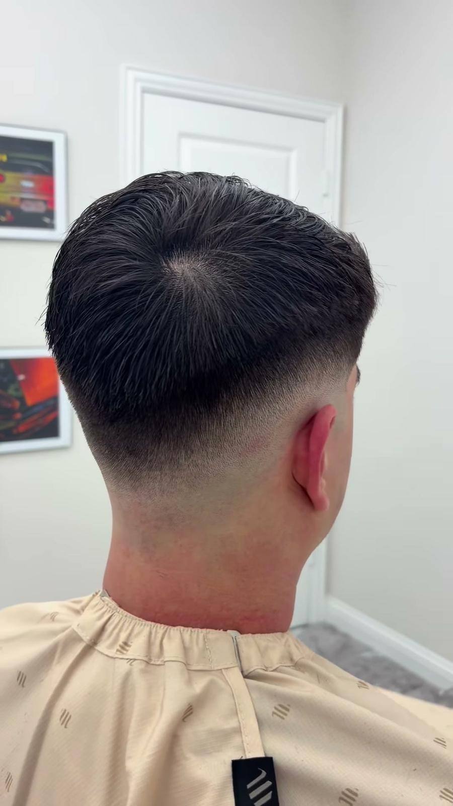 Back of a fresh mid drop fade, the hair blended down to the skin at the neckline